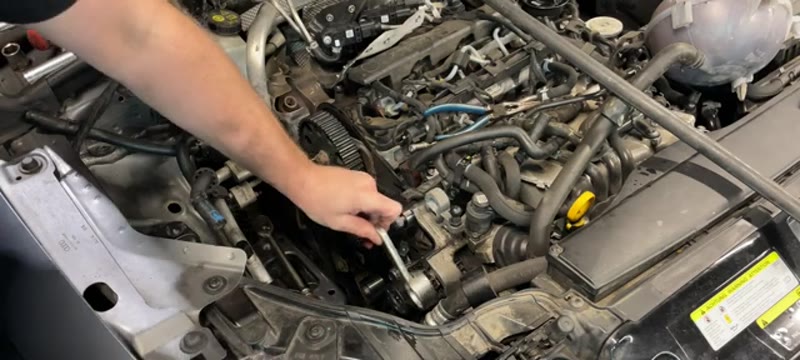 Loosening the fuel pump sprocket bolt with a holding tool on the Audi A3