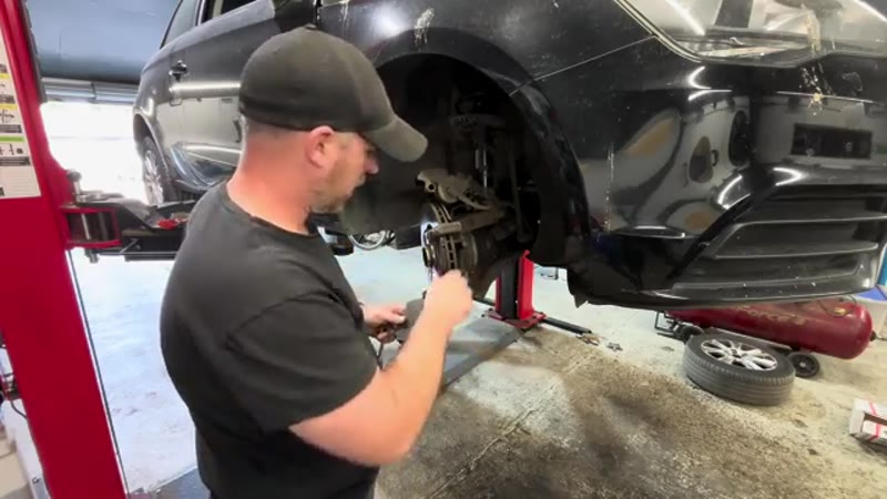Inspecting the worn front brake pads on the Audi caliper