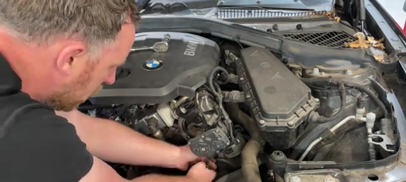 Undoing the 13mm tensioner mounting bolts on the BMW 1 Series alternator