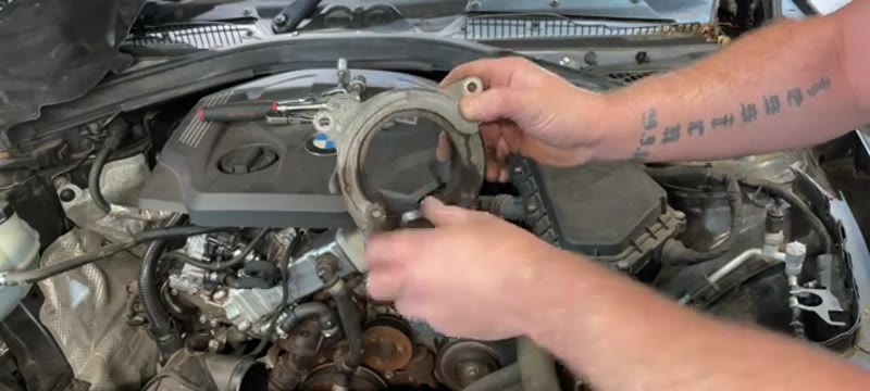 Checking the bearing on the old auxiliary belt tensioner removed from the BMW 116d