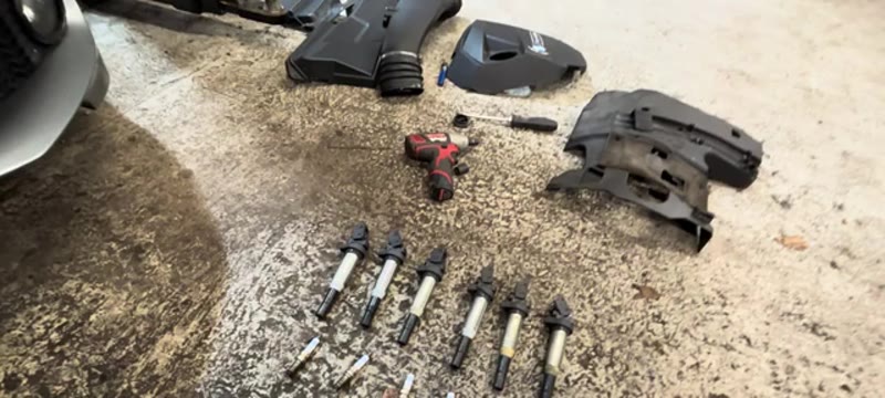All six spark plugs and coil packs from the BMW 335i laid out for inspection