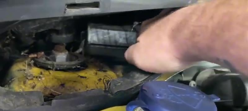 Hand folding down the front cover of the Citroën DS3 pollen filter housing to reveal the filters inside