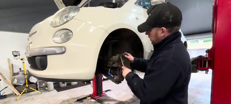 Cleaning the inside of the Fiat 500 brake caliper with a wire brush, avoiding the piston seal