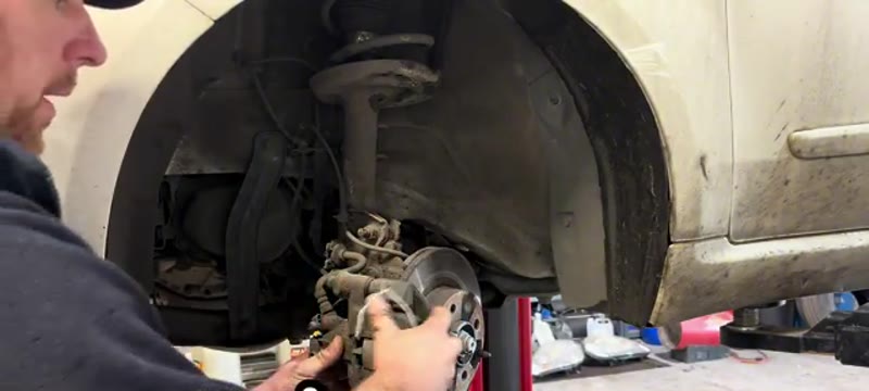 Undoing the caliper carrier bolts behind the hub on a Fiat 500 front brake