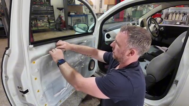 Peeling back the vapour membrane on the Fiat 500 door to reach the handle mechanism
