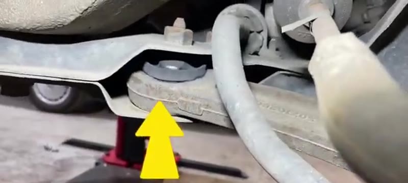 Inspecting the lower ball joint rubber boot on a Fiat 500 with the front wheel removed