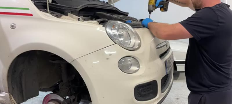 Removing the Torx bolts along the top edge of the Fiat 500 front bumper to release the corner