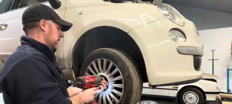 Removing the front wheel of a Fiat 500 with an impact gun to access the shock absorber
