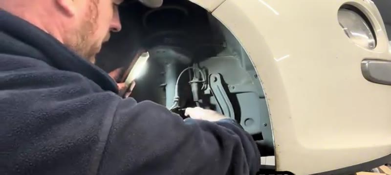 Unclipping the ABS sensor wire and brake hose from the Fiat 500 shock absorber bracket
