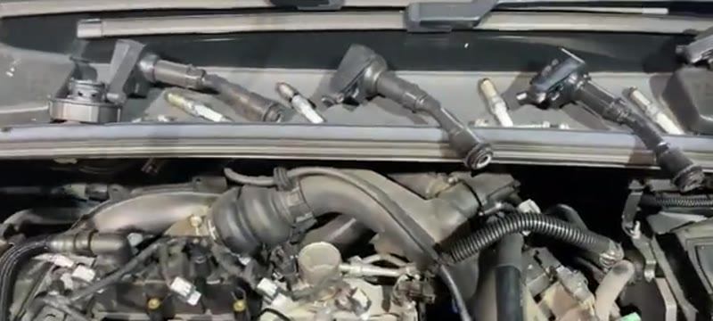 Ignition coils and spark plugs removed from a Ford Focus petrol engine and laid out along the scuttle panel