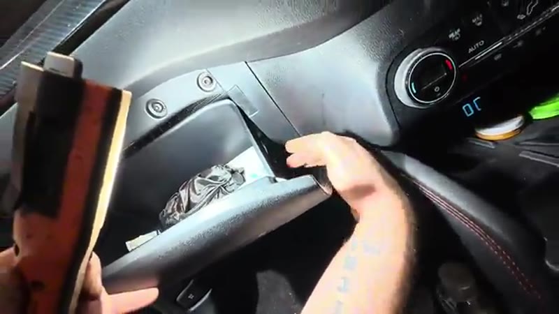 Releasing the glove box side tabs to drop it down on the Ford Kuga
