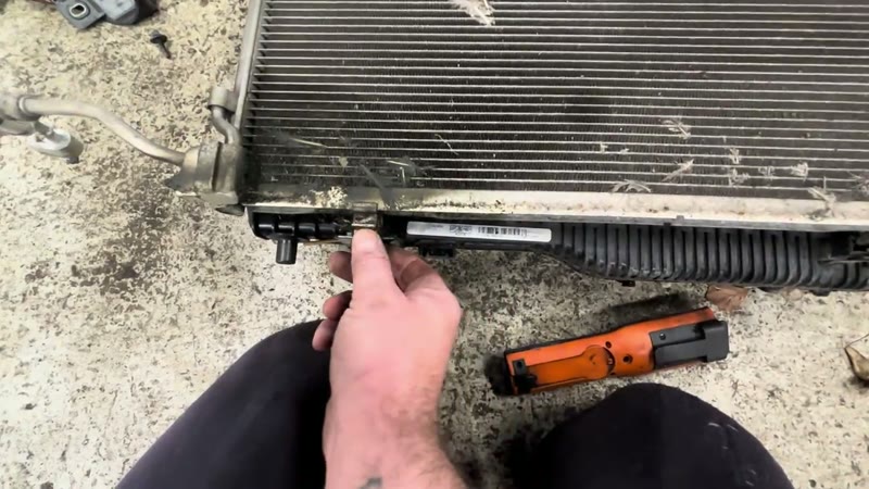 Pulling the hidden release tabs on the underside of the Ford Puma condenser mounting