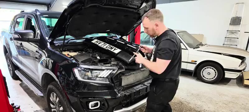 Undoing the top bumper bolts behind the headlight with a long extension on the Ford Ranger