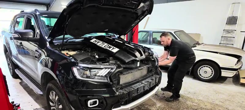 Pulling the front bumper sharply to release its side clips on the Ford Ranger