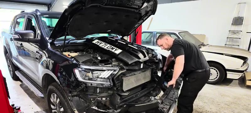 Disconnecting the fog light and parking sensor plugs as the Ford Ranger bumper comes away