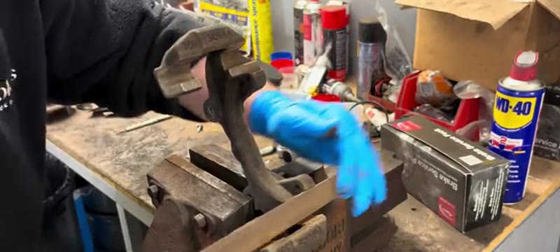 Cleaning the caliper carrier in the bench vice with a wire brush and file