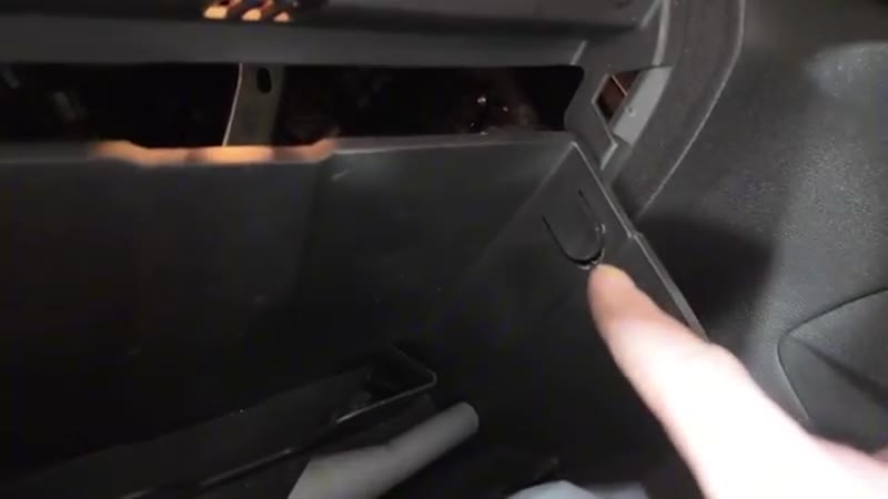 Pressing the tabs to drop the glove box down and reveal the passenger compartment fuse box
