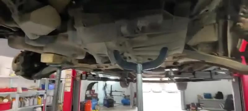 Gearbox supported on the transmission jack ready to be lowered out of the Transit Custom