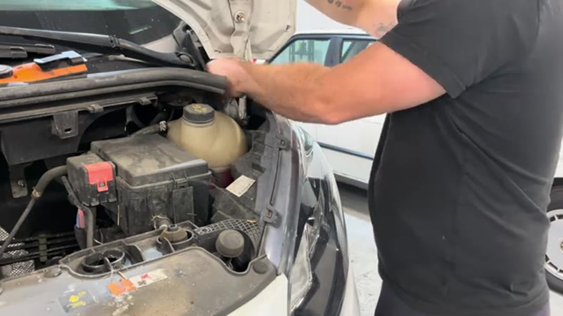 Removing the two T30 Torx bolts that hold the headlight unit in place on a Ford Transit Custom