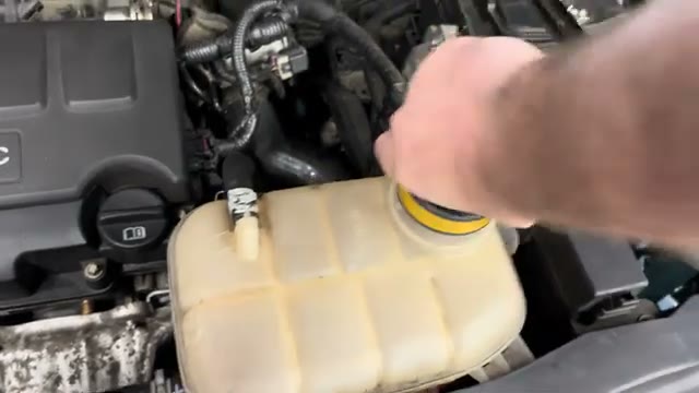 Fitting the pressure tester adapter cap onto the coolant expansion tank