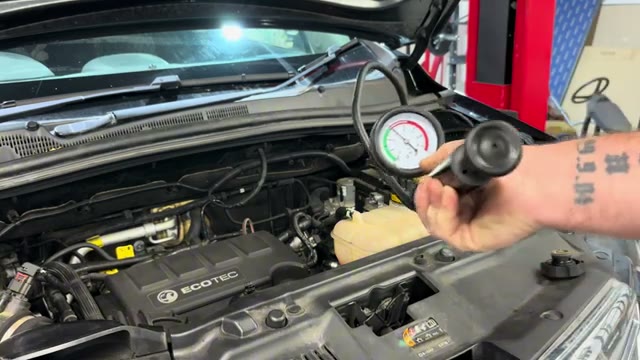 Reading the coolant pressure tester gauge to see whether the system holds pressure