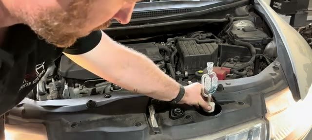 Holding the combustion leak tester over the Honda Civic radiator neck for the sniff test