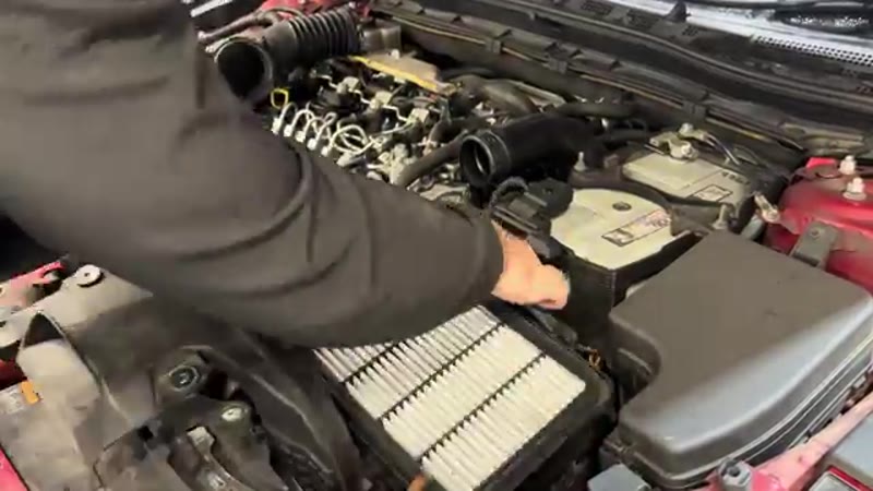 Lifting the battery out of the Mazda 3 engine bay for access to the vacuum pump