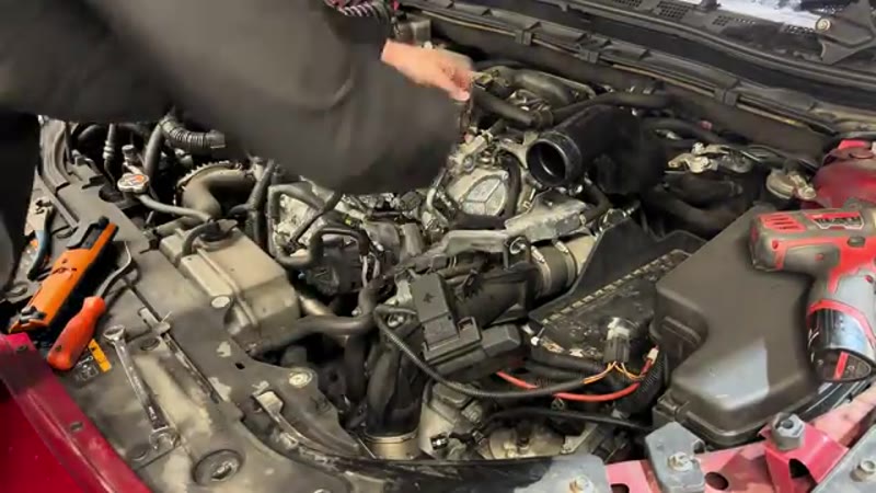 Disconnecting the vacuum hose and bracket next to the vacuum pump on a Mazda 3