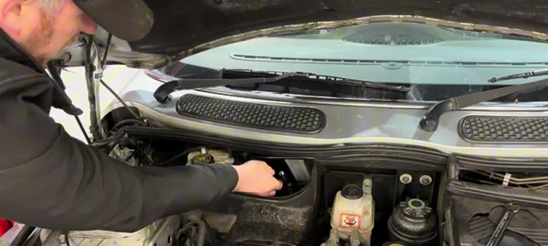 Squeezing the tab to disconnect the electrical plug on the Mini Cooper brake master cylinder