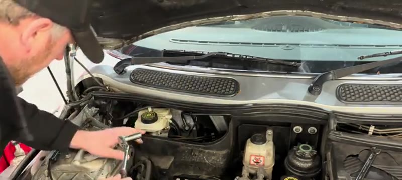 Undoing the two 13mm mounting bolts on the Mini Cooper brake master cylinder