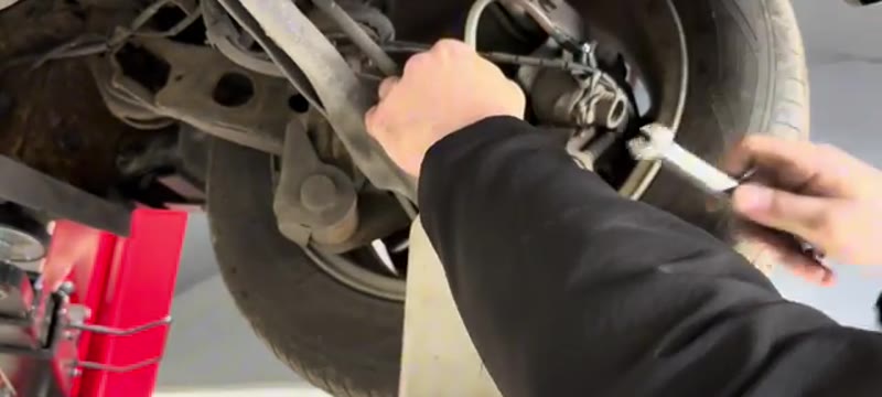 Bleeding a brake caliper nipple on the Mini Cooper with a spanner and bleed bottle