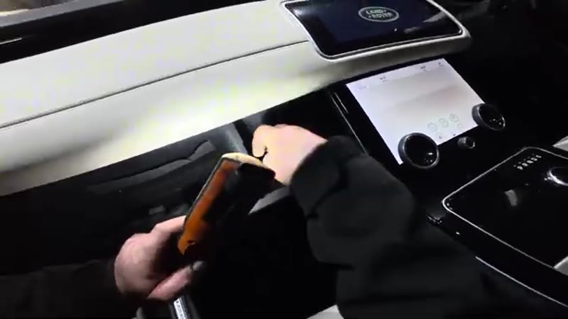 Pushing in the side tabs to drop the glove box down on a Range Rover Velar