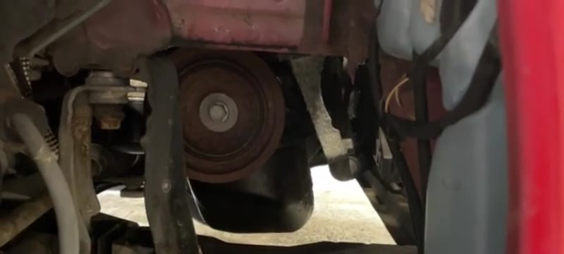 View through the wheel arch to the crank pulley and auxiliary belt on a Renault Clio