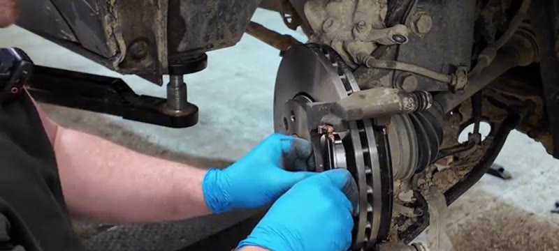 Slotting the new brake pads into the cleaned caliper carrier on the Trafic