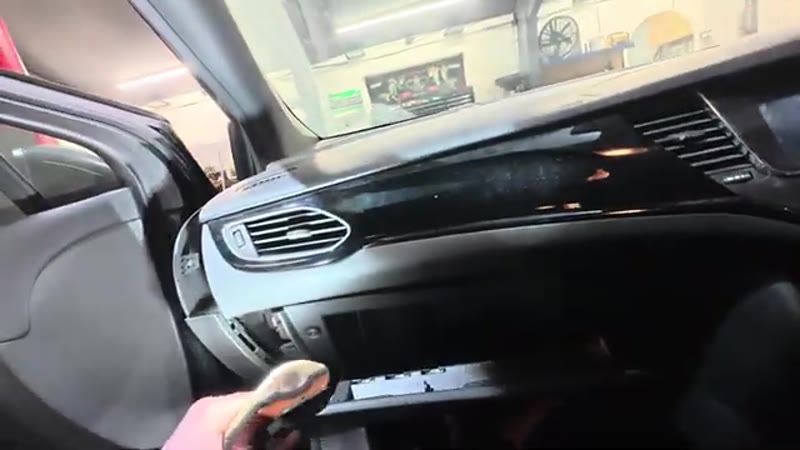 Lining the glove box back up under the dashboard of the Vauxhall Astra