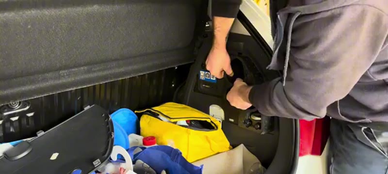 Lifting the tyre inflator kit out of the boot side compartment on the Vauxhall Corsa