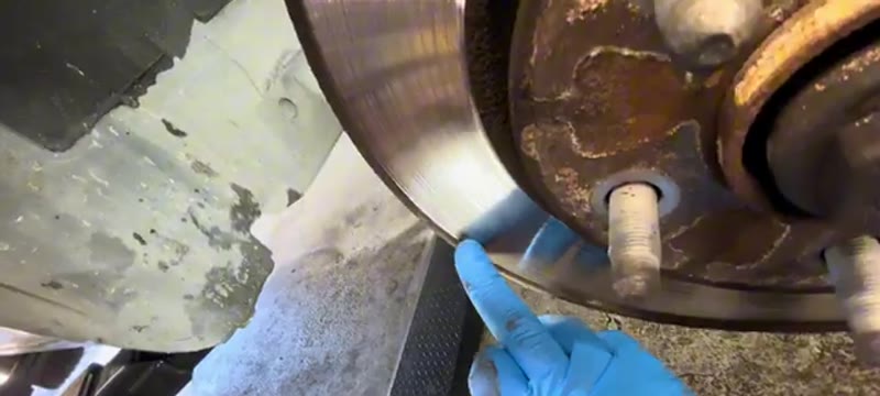 Inspecting the heavy lip on the worn front brake disc of a Vauxhall Insignia with the wheel removed