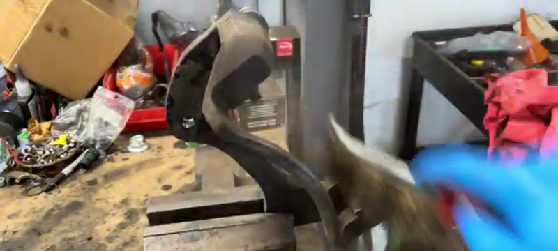 Cleaning the caliper carrier slider surfaces with a wire brush on the bench