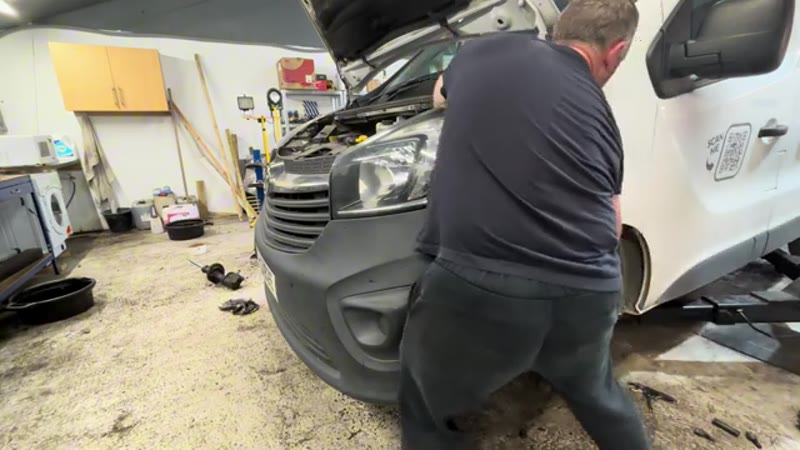 Holding the new shock absorber up into position in the Vauxhall Vivaro wheel arch