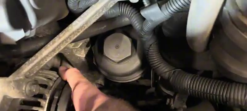 Hand reaching into the Volvo XC90 engine bay to wiggle the alternator free of its mounting