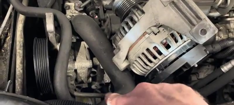 Volvo XC90 alternator being eased past the power steering line for clearance