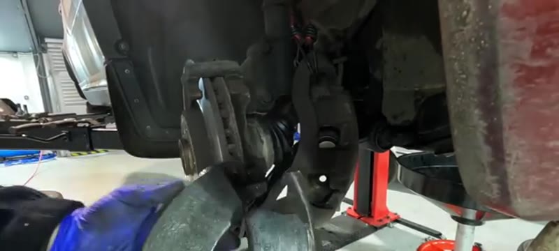 Old worn brake pads being removed from the Volvo XC90 caliper carrier