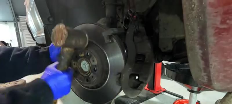 Tapping the old brake disc free of the Volvo XC90 hub after removing the retaining bolt