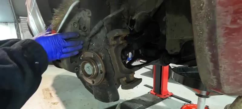 Cleaning rust from the Volvo XC90 hub and carrier mating surfaces with a wire brush