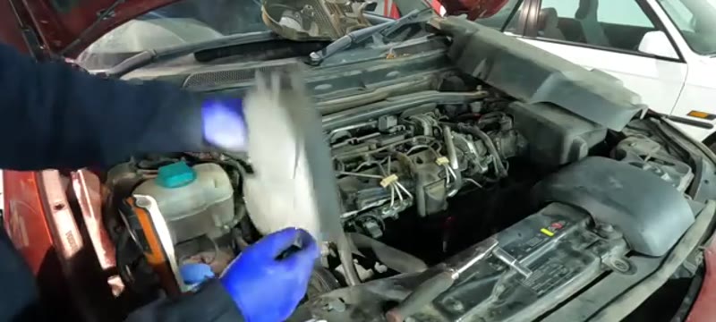 Undoing the two T30 Torx bolts and lifting away the auxiliary belt cover on the Volvo XC90 D5