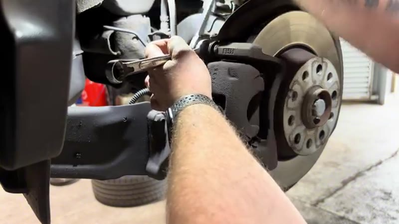 Undoing the 13mm caliper guide pin bolt with a spanner on the VW Tiguan