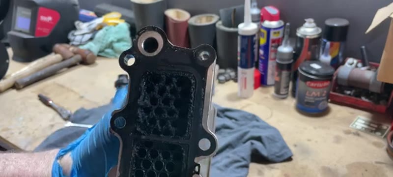 Separated EGR cooler from a VW Transporter on the bench showing heavy carbon blockage before cleaning
