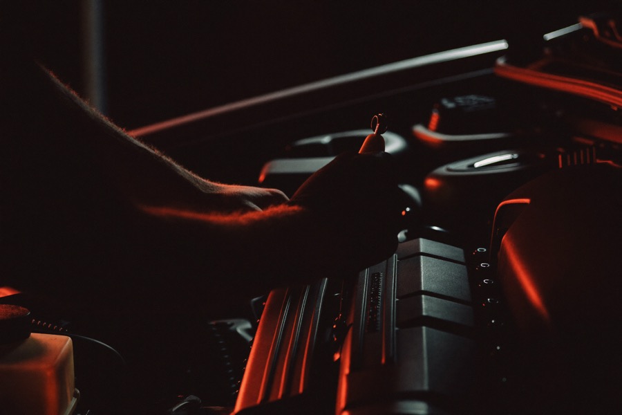 Mechanic working on a car engine bay with a spanner