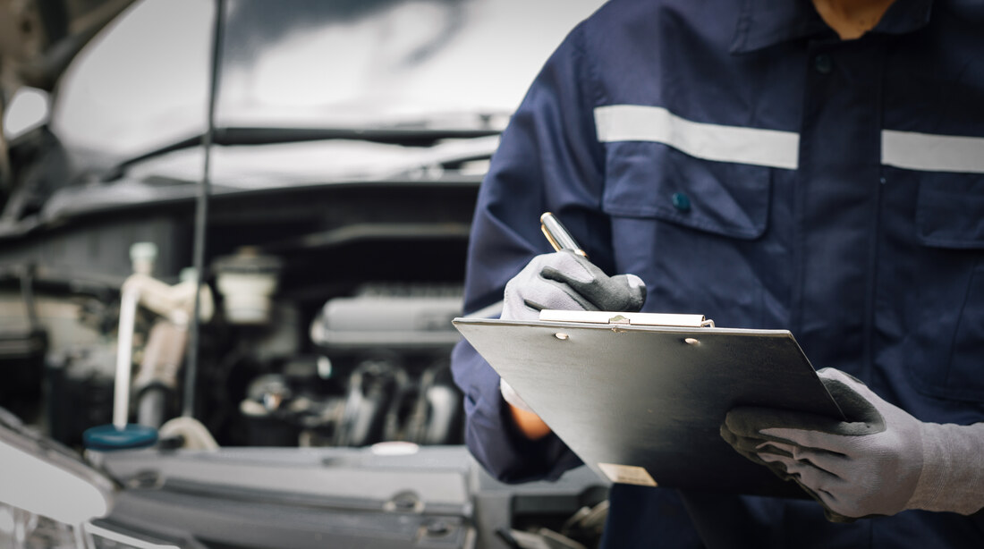 Mechanic filling in a service checklist on a clipboard